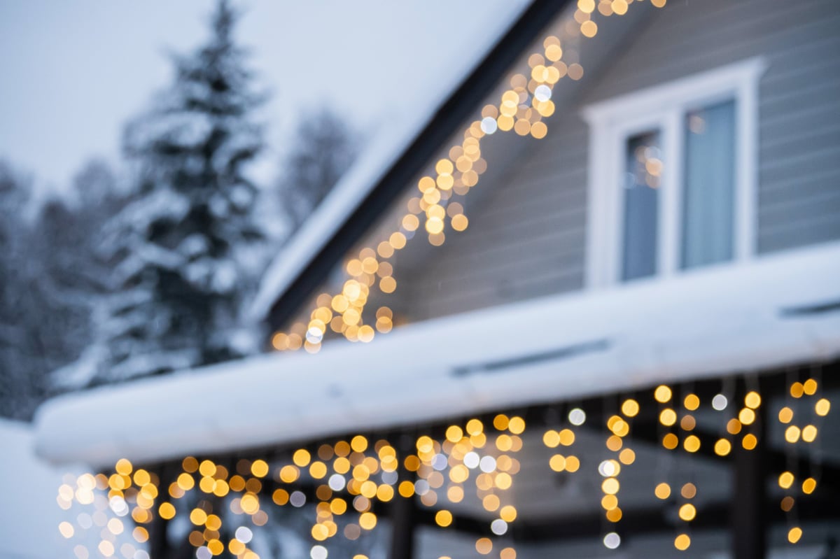 Snowy blurred winter house in forest with bokeh of festive Christmas lights